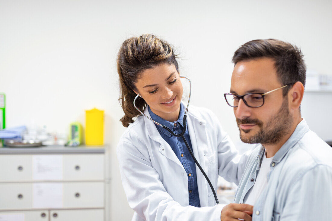 Young doctor is using a stethoscope listen to the heartbeat of the patient. Shot of a female doctor giving a male patient a check up
